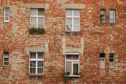 Aged red brick wall texture of house facade with windows. Stock Photos