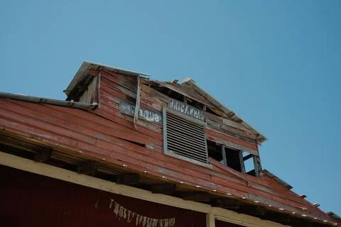 Aged red wooden building with an array of windows and boarded-up windows 스톡 사진