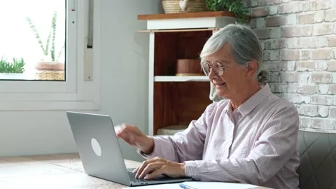Aged remote worker. Concentrated senior female in glasses work on laptop fr.. Stock Footage 236928461