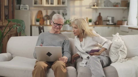 Aged spouses use gadgets, old woman using mobile app and elderly man with laptop Stock Footage 308527455