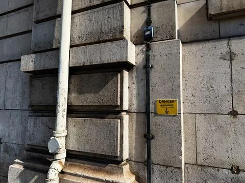 Aged stone wall with pipe and danger sign on classic Paris France building .. Stock Photos