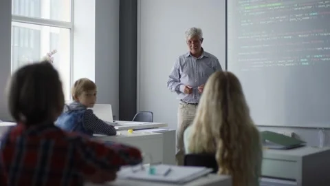 Aged teacher asking question explaining computer coding to children Stock Footage 142491259