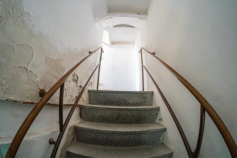 An aged underground staircase inside an old castle, lit by filtered light fro Stock Photos