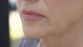 Aged woman touching her wrinkled skin, nostalgic memories, anti-aging cosmetics 4k or 4k+ Resolution