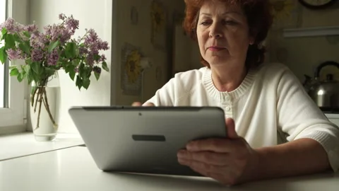 Aged woman using a digital tablet PC at home Stock Footage 142340461