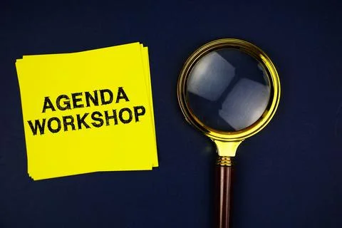 Agenda Workshop text on sticky note with magnifying glass on navy blue back.. Stock Photos