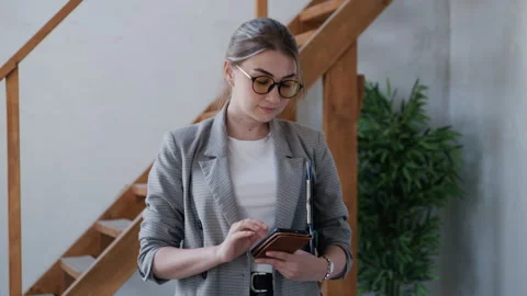 Agent with Documents Types on Phone in New Apartment with Plant and Stairs 库存影片 311825188