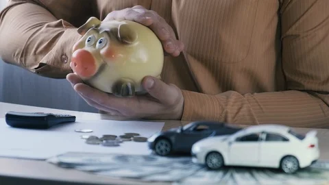 Agent or auto dealer stroking a piggy bank on the background of toy cars Stock Footage 119419628