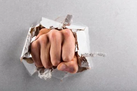 Aggression concept, wall is broken through by a fist Stock Photos