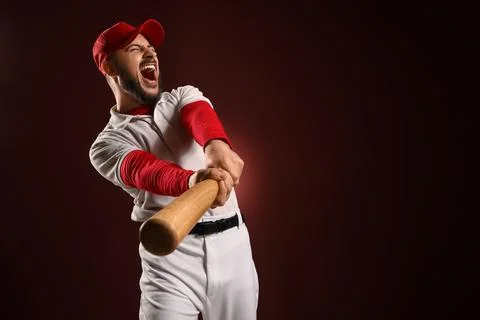 Aggressive baseball player swinging bat with intense expression, sports compe Stock Photos