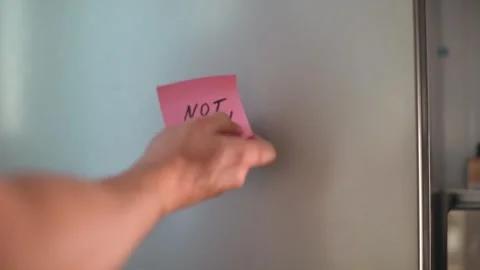 An aggressive hand rips off a "Not Now" reminder sticker from a refrigerator Stock Footage 339096644