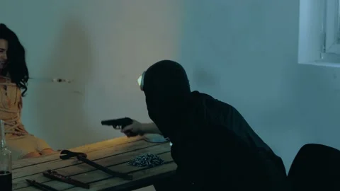 Aggressive man in black balaclava threatening frightened woman with the gun Stock Footage 238987336