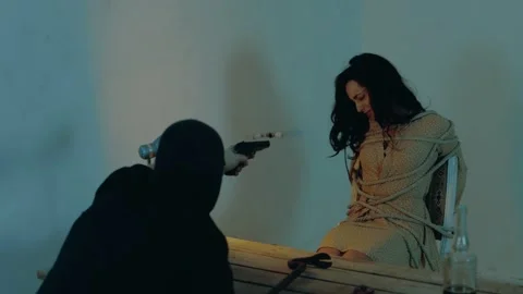 Aggressive man in black balaclava threatening frightened woman with the gun Stock Footage 255143243