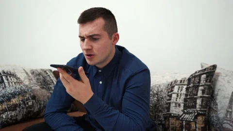 Aggressive man talking on the phone while sitting on the couch at home Video stock 145982009