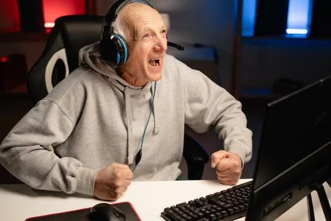Aggressive senior man plays computer games retirement at home. Elderly stream Stock Photos