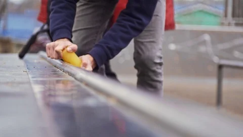 Aggressive skater applying wax on a box for sliding tricks at the skatepark Stock Footage 122511432