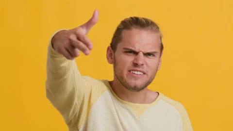 Aggressive Young Guy Shooting At Camera With Finger Gun Over Yellow Background Stock Footage 161713213