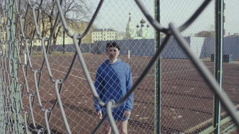 Aggressive young man talking something on a sports field behind a metal fence Stock Footage 74516967