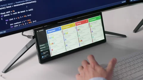 Agile Developer Checking Kanban Board On Secondary Screen While Writing Code Stock Footage 328709642