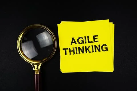 Agile Thinking text on sticky note with magnifying glass on black background Stock Photos