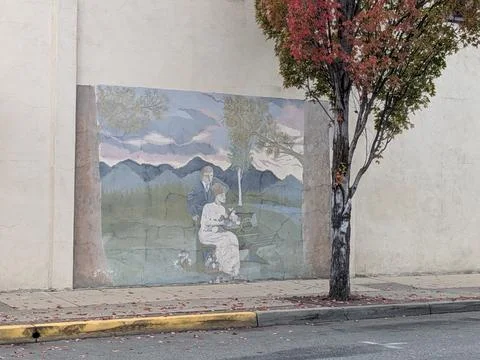 An aging mural on a building wall shows a man and kneeling woman 写真素材