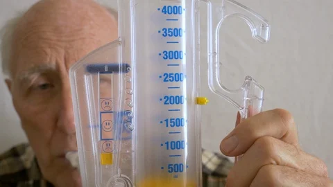 Aging senior practices breathing with incentive spirometer device Video stock 102131426