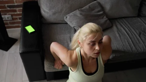 Agirl makes triceps bench dip. Smartphone lies nearby with chroma key screen Stock Footage 127884893