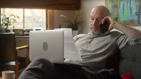 Agitated man talking to support on a smartphone hangs up and starts to work 스톡 동영상 133290248