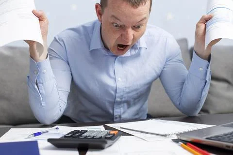 Agitated panicked man using calculator for calculate domestic bills at home Stock Photos