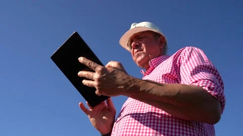 Agricultural engineer enters data on a tablet. He wears a checkered shirt a.. Stock Footage 228984900