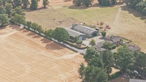 Agricultural farmstead surrounded by arable fields and woodland near Stock Footage 346257548