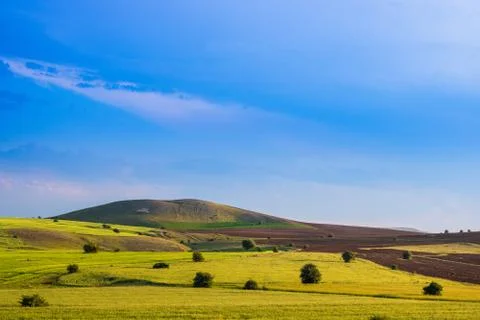 Agricultural fields and sparse trees. Hills and dramatic sky on the backgroun Foto stock