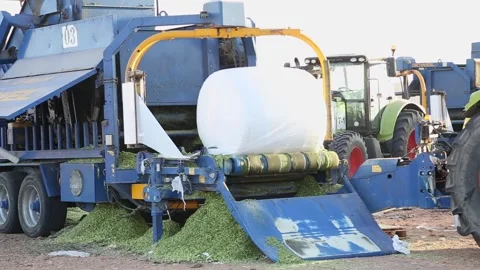 Agricultural machine wrapping a silage bale in plastic wrap on a farm 스톡 동영상 318831198