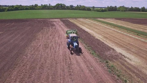 Agricultural tractor with trailer for plowing working on arable field Stock Footage