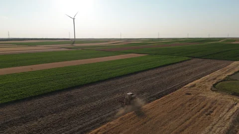 Agricultural tractor is working on the field with wind turbines. Stock Footage 312077187