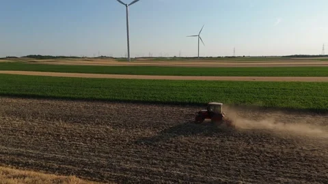 Agricultural tractor is working on the field with wind turbines. Stock Footage 312077509