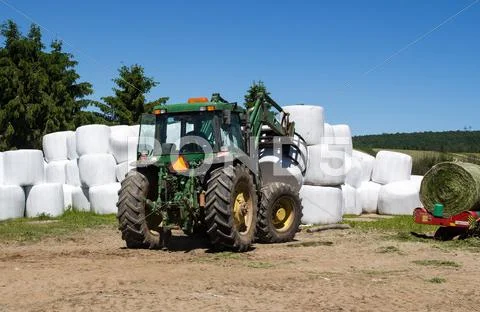 Agriculture machinery picking up hay roll Stock Photos