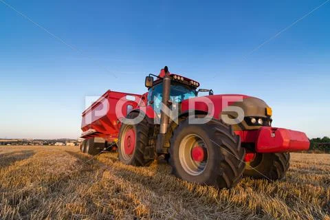 Agriculture tractor and trailer on a stubble field Stock Photos