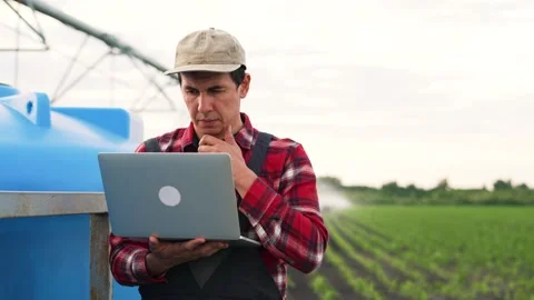 Agriculture.Farmer engineer is work with laptop in field.Automatic irrigation Vídeos de archivo 246960035