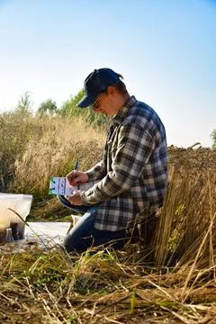 Agriculturist taking notes in soil sampling information sheet at field Stock Photos