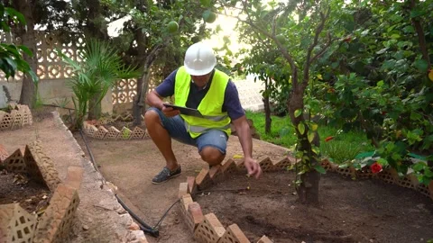 Agronomist engineer checks irrigation pipe of a garden, controls irrigation w Stock Footage 219506232