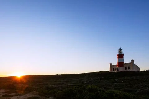 Agulhas lighthouse at southernmost tip of Africa at sunset Stock Photos