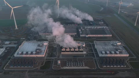 Ai cloud data center emitting smoke amidst wind turbines Stock Footage 334056590