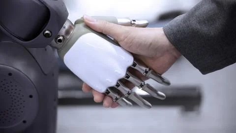 AI Robot shaking hands with man. Close up shaking hand with robotic arm Foto stock