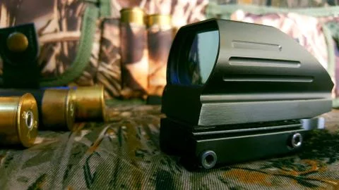Aims red dot sight, ammunition and bandoleer on a camouflage background, wall Stock Photos