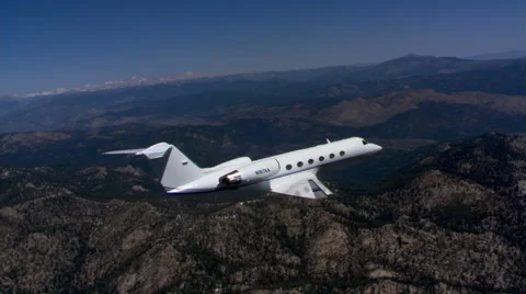 Air-to-air side view of small jet above rugged terrain Stock Footage 59476706