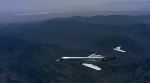 Air-to-air view of jet flying over forested mountains Stock Footage 59476318