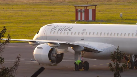 Air Astana Embraer E190-E2 parked at airport while ground crew works Stock Footage 341435951