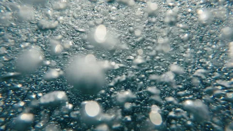 Air bubbles and sun glare on evening time on surface of water at sunset, Stockbeeldmateriaal 253336692