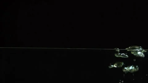 Air bubbles beautifully float to the surface of the water on a black background, Video stock 116020865